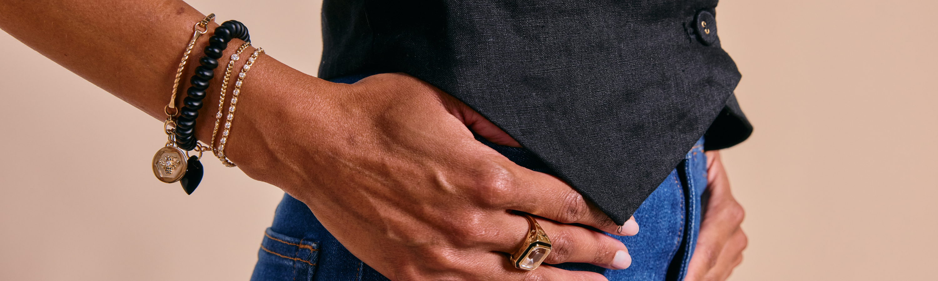 Bracelets collection image featuring a model wearing layered gemstone and charm bracelets styled in a clean, editorial setting