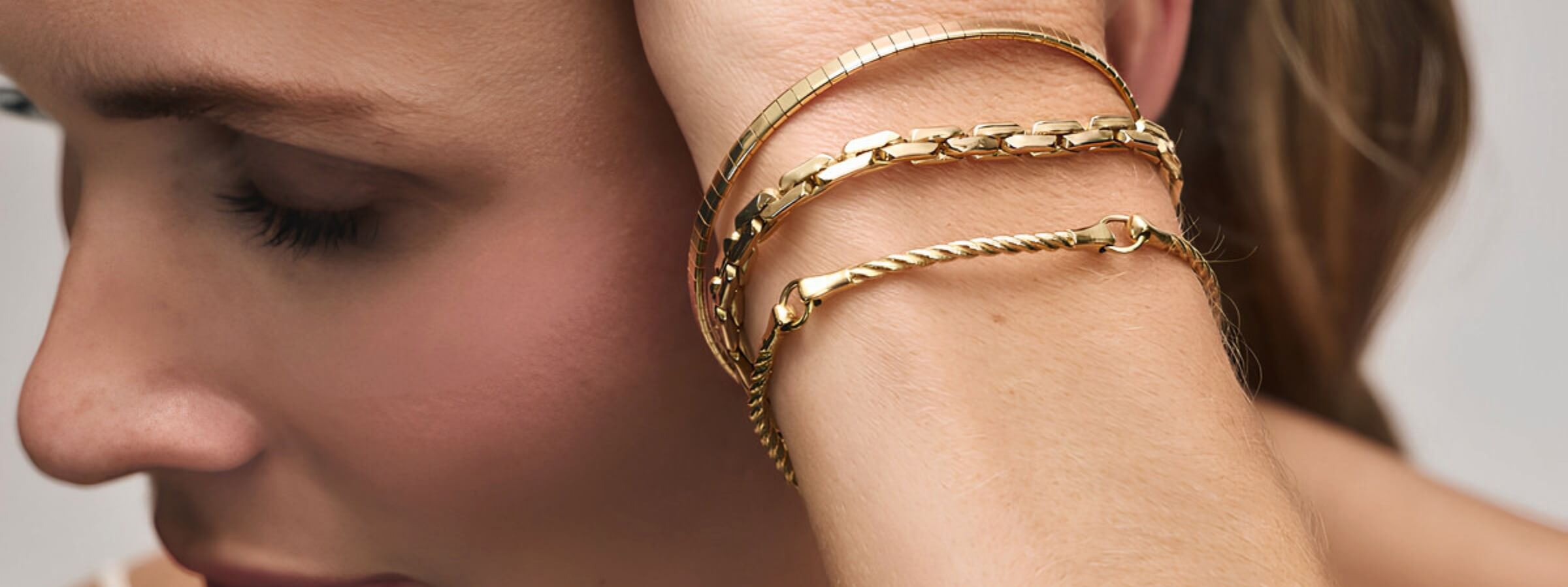 Bracelets collection image featuring a model wearing layered gemstone and charm bracelets styled in a clean, editorial setting