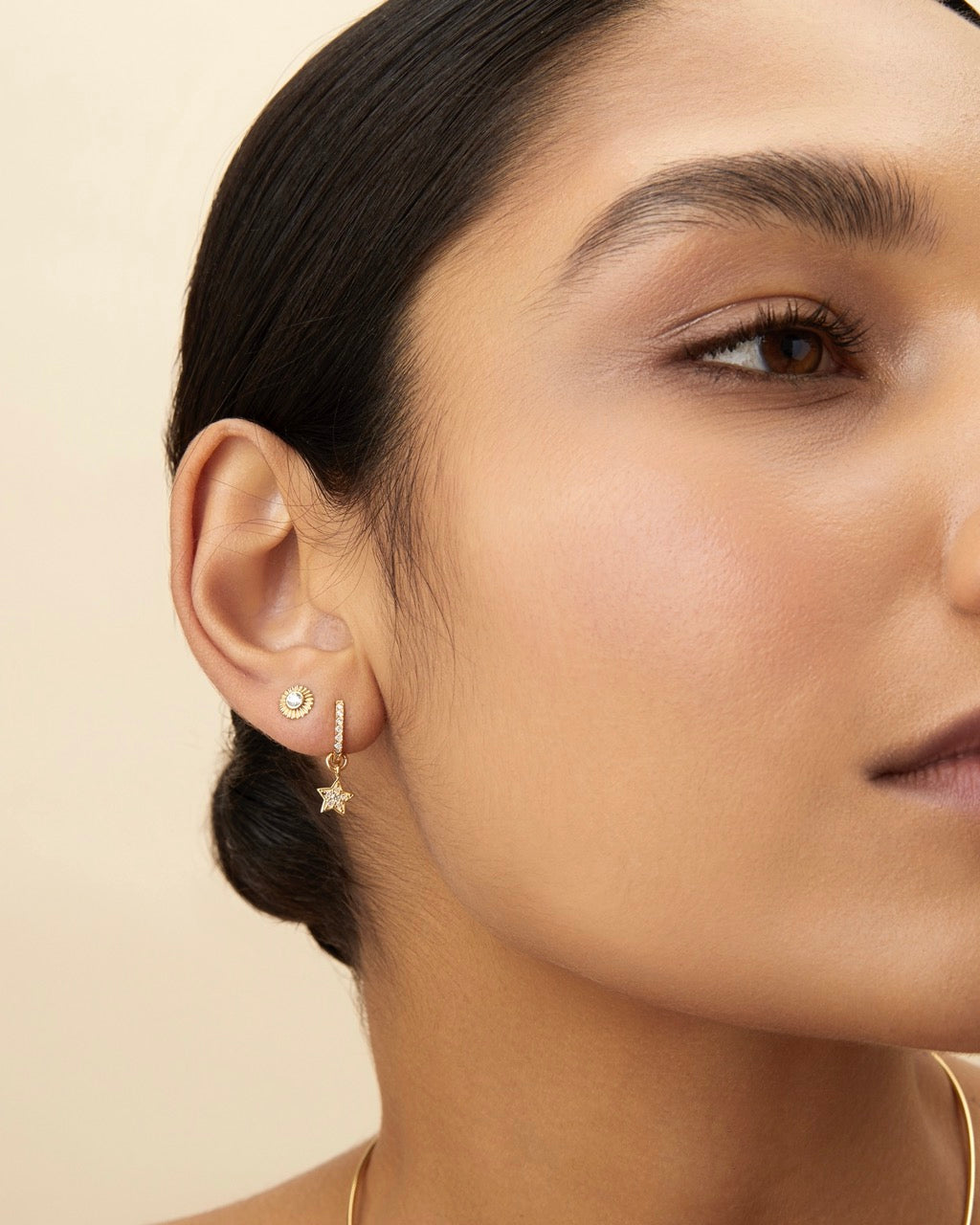 Model wearing a single Clarity Stud earring in 14k gold with diamond sunburst center, shown in side profile.