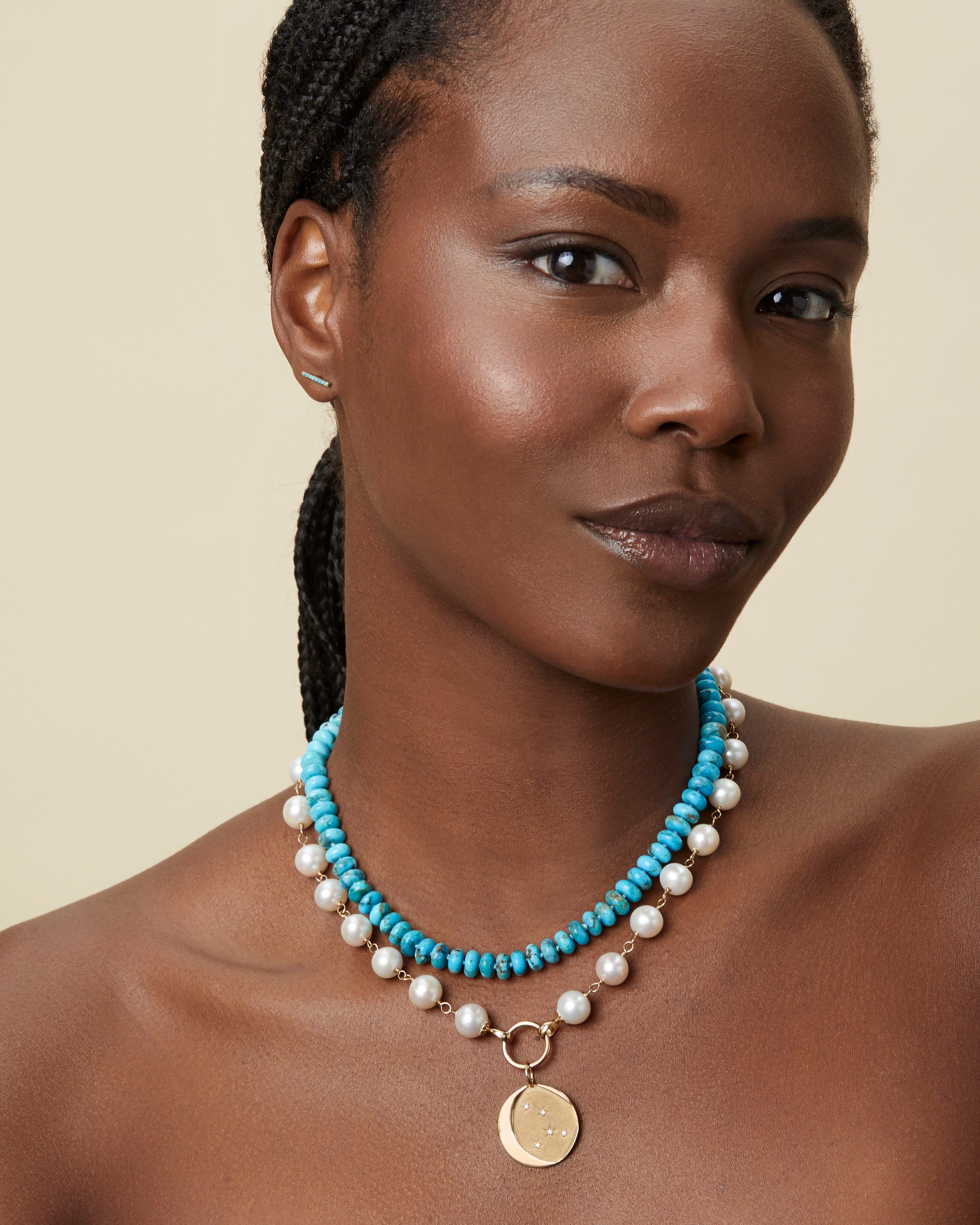 Model wearing the Estrella Charm layered with turquoise bead necklaces