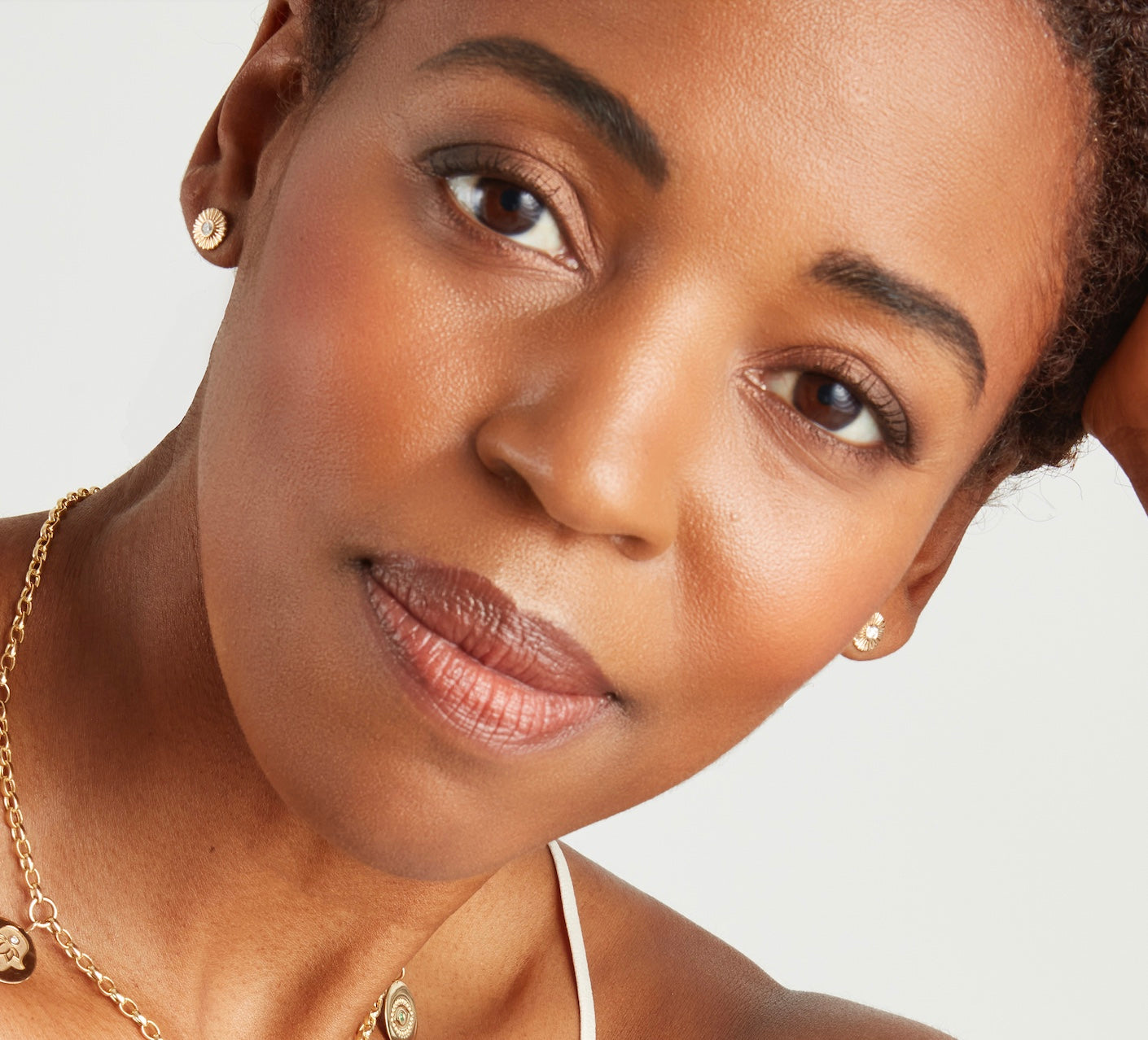 Model wearing the Clarity Studs, petite gold and diamond sunburst earrings styled for everyday wear.