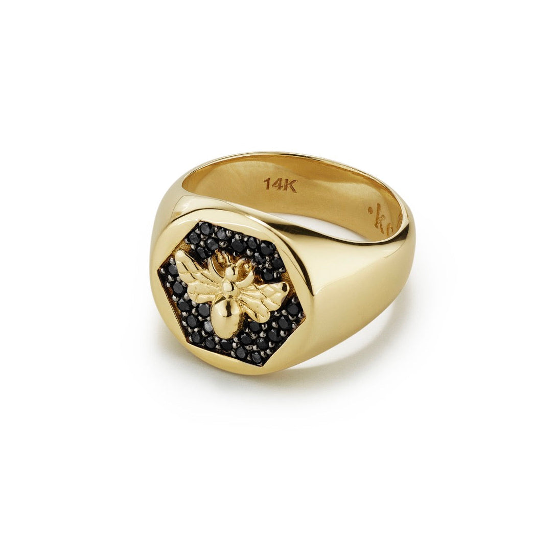 Gold ring with a bee design and black stones on a white background