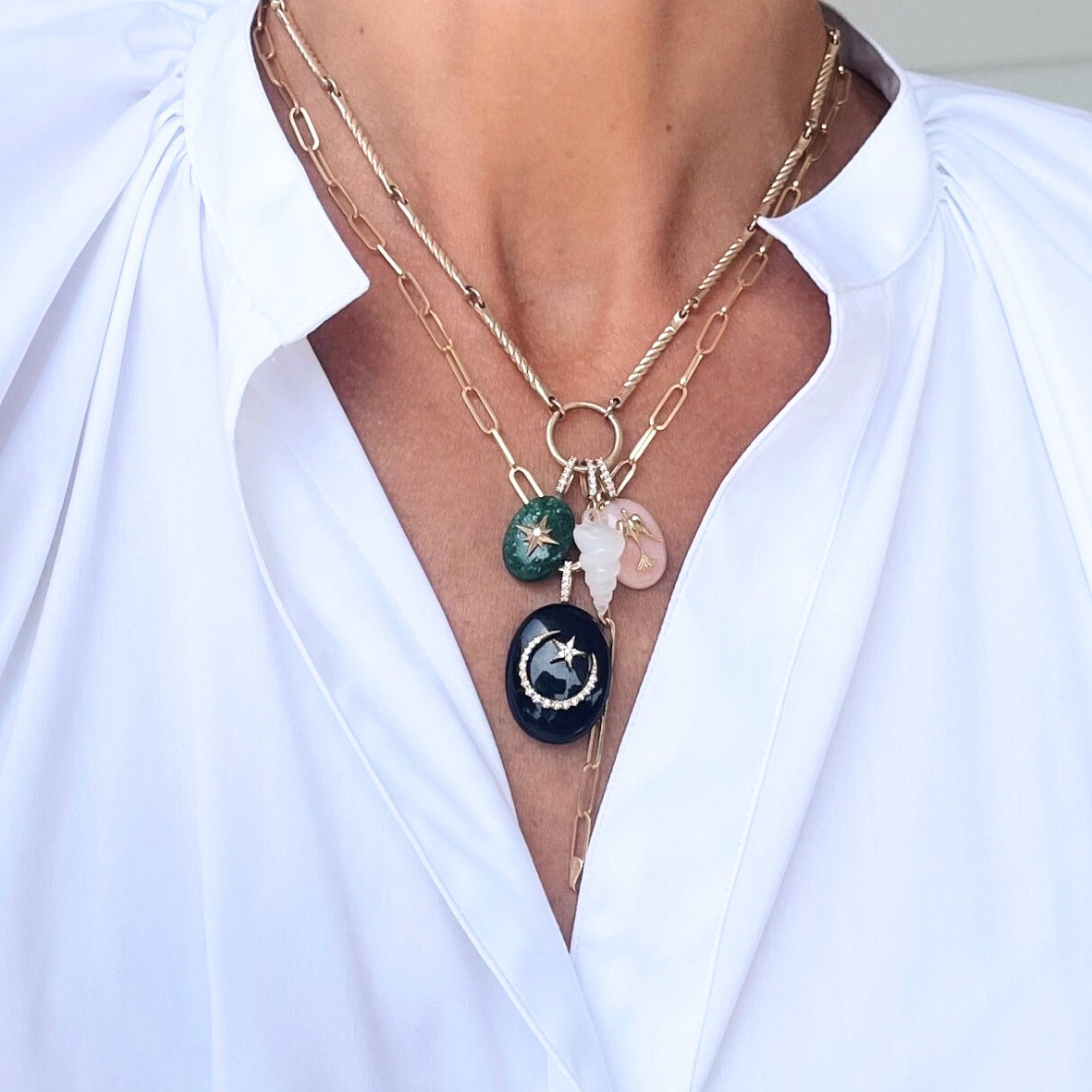 Layered gemstone starburst pendants and black onyx moon-and-star pendant worn on a silver chain around the neck