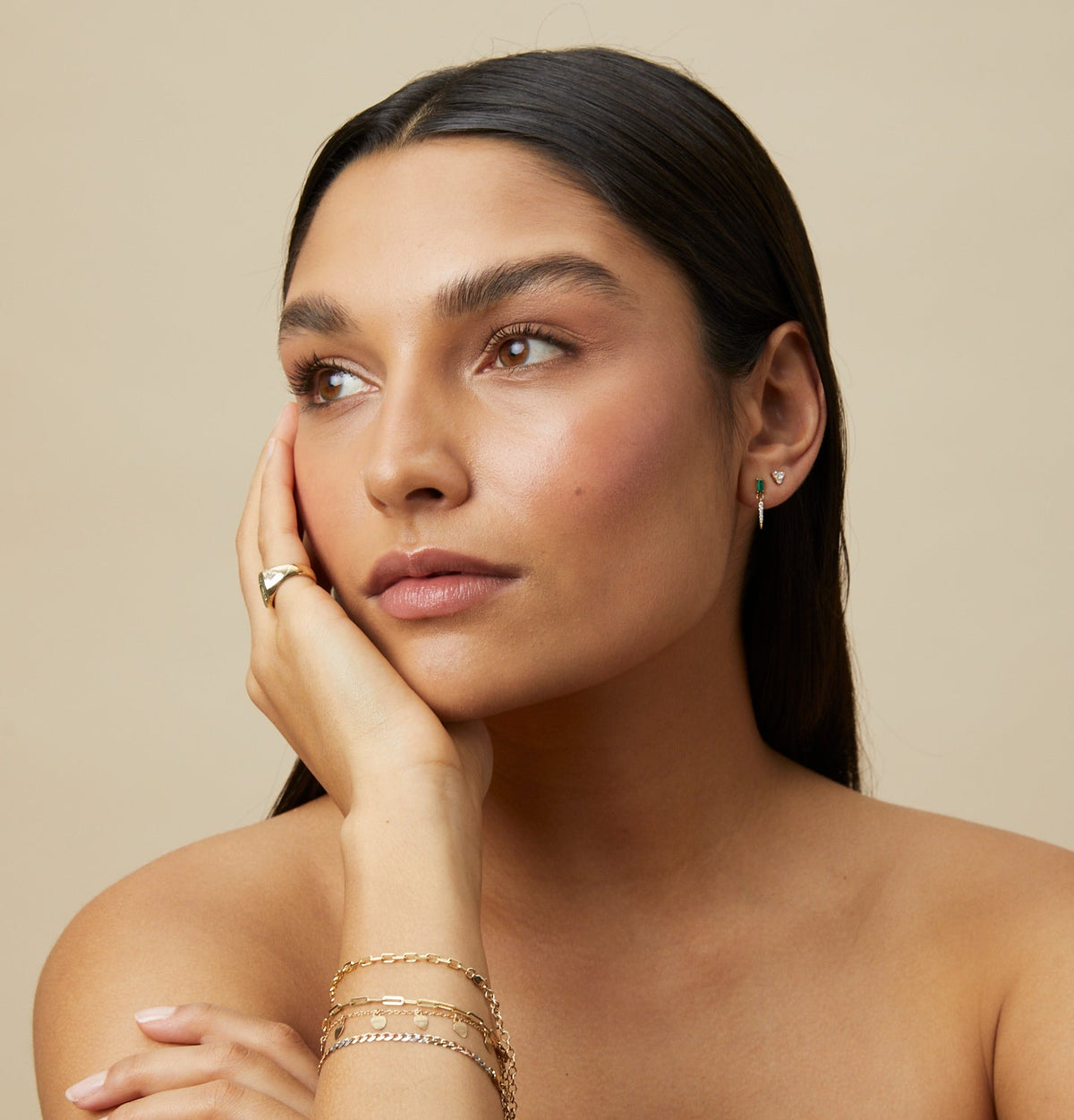 Emerald Drop Earrings worn by a model with gold bracelets and ring