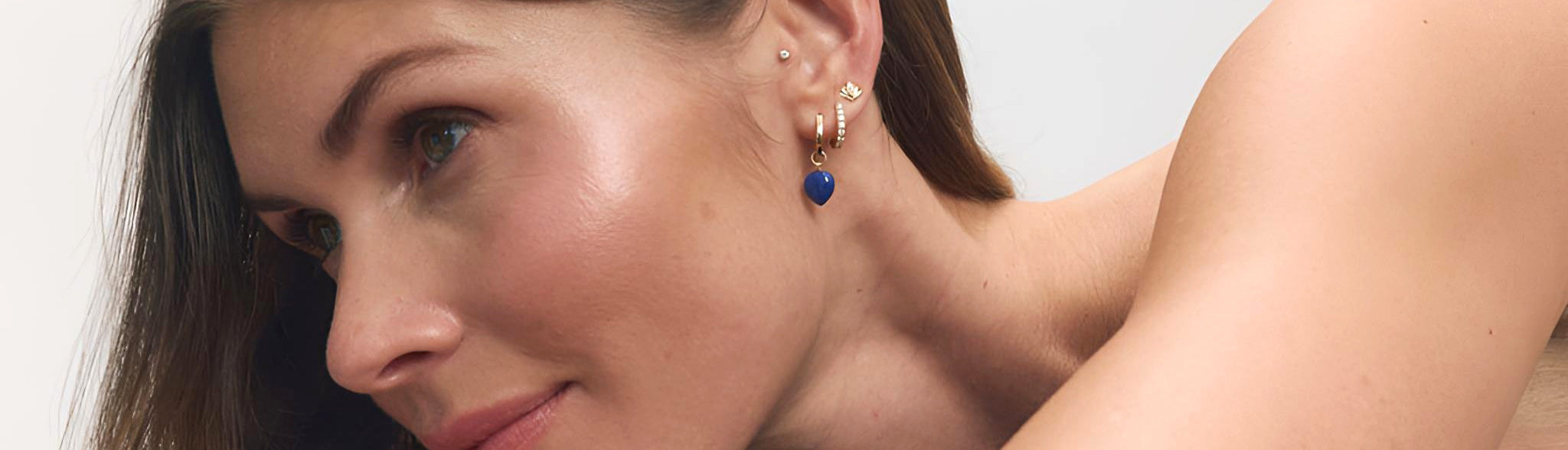 Earrings collection image featuring a model wearing delicate earrings styled in a clean, editorial setting