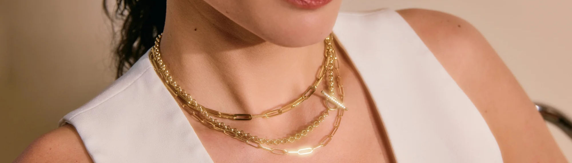 Chains collection image featuring a model wearing layered gold chains styled in a clean, editorial setting