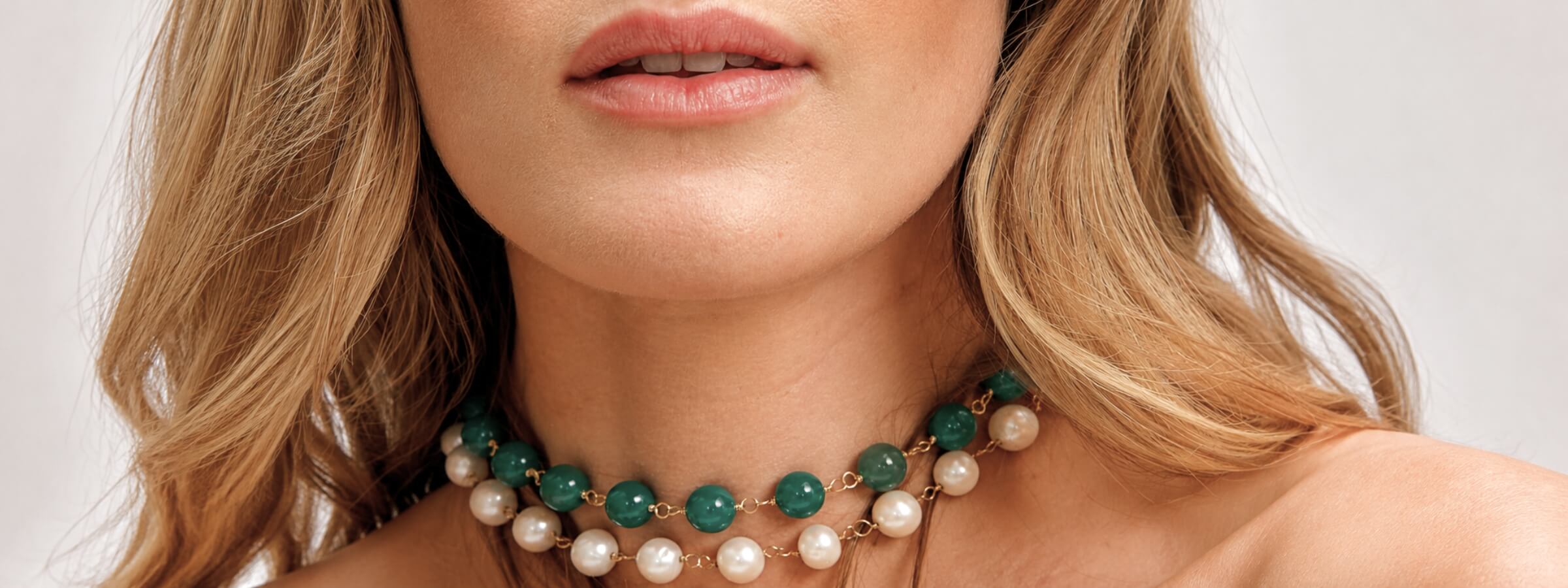 Necklaces collection image featuring a model wearing a layered gemstone necklace styled in a clean, editorial setting