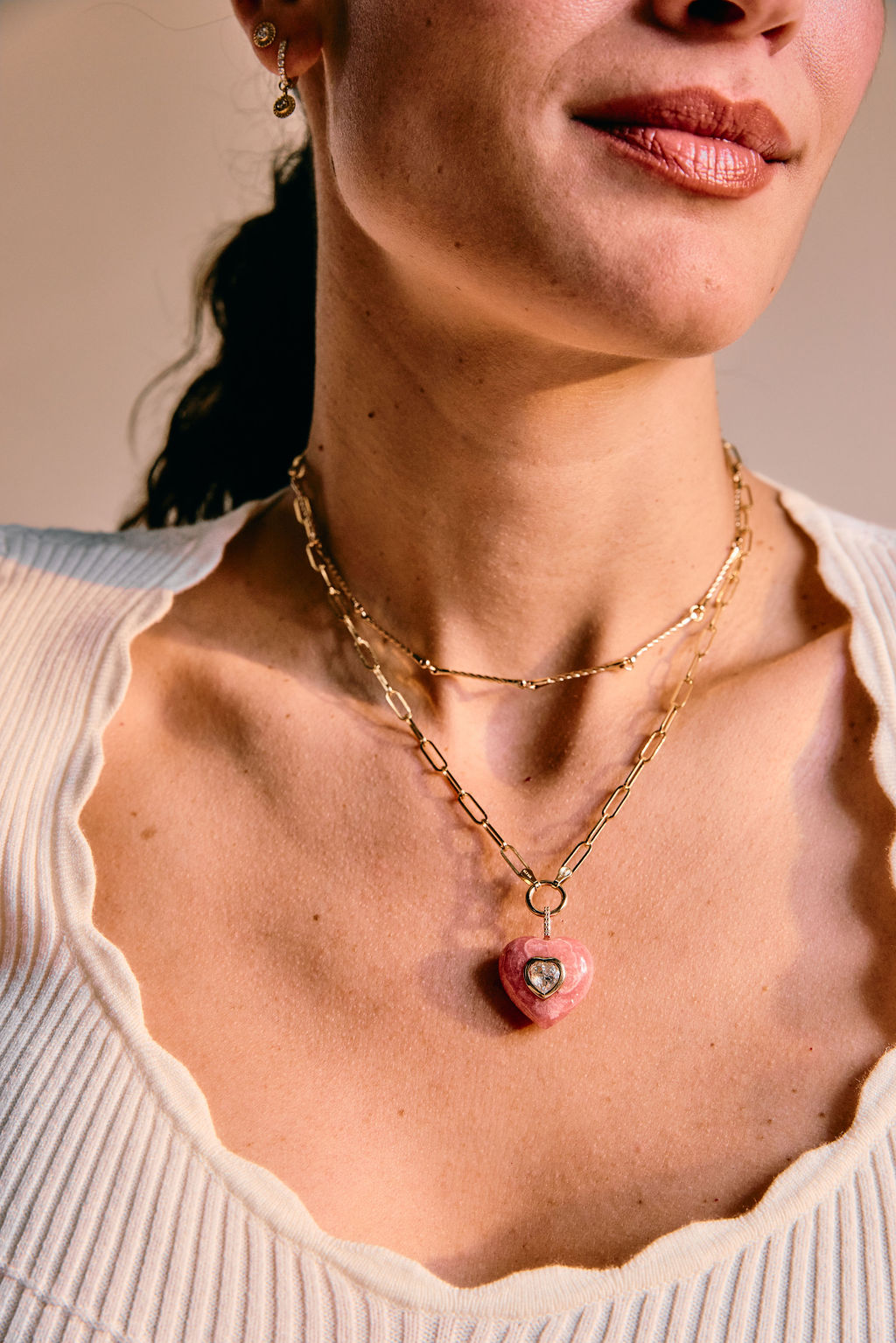 Close-up of a woman wearing a gold necklace with a heart pendant.