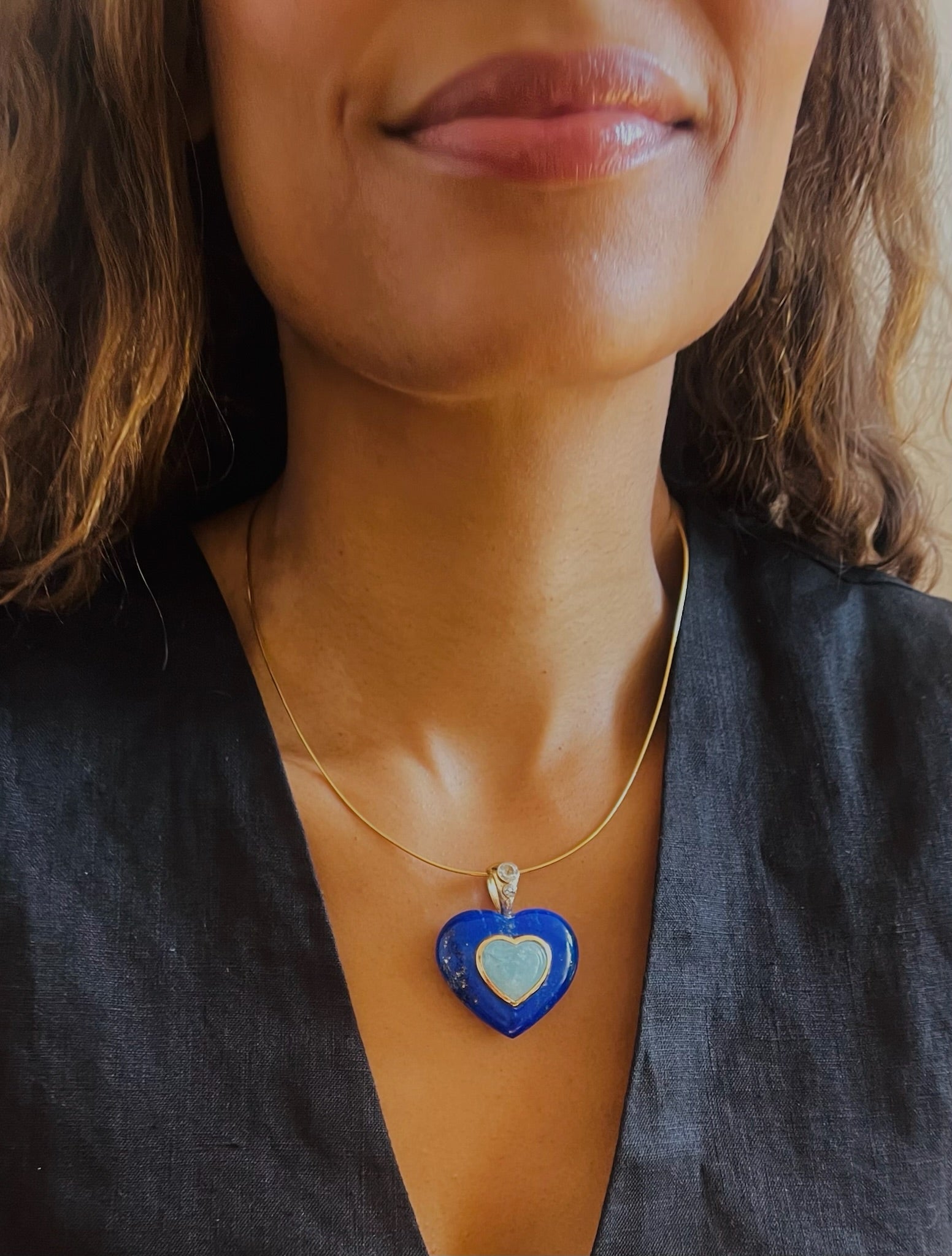 A hand-carved Lapis Lazuli heart pendant with aquamarine stone at center. Graduated Rose-cut Blue Topaz stones on 14k gold bail 