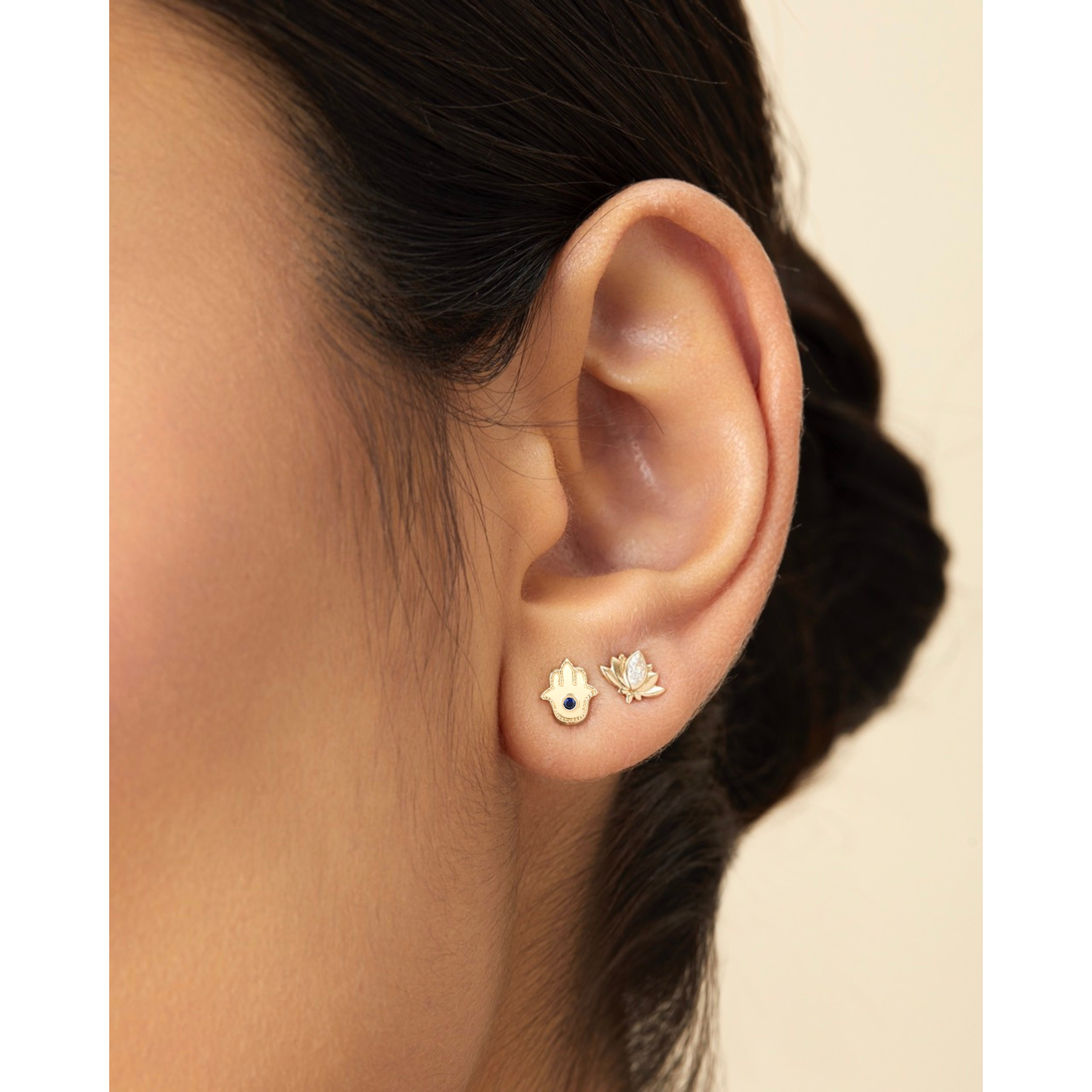 Close-up of an ear wearing gold earrings with a blurred background