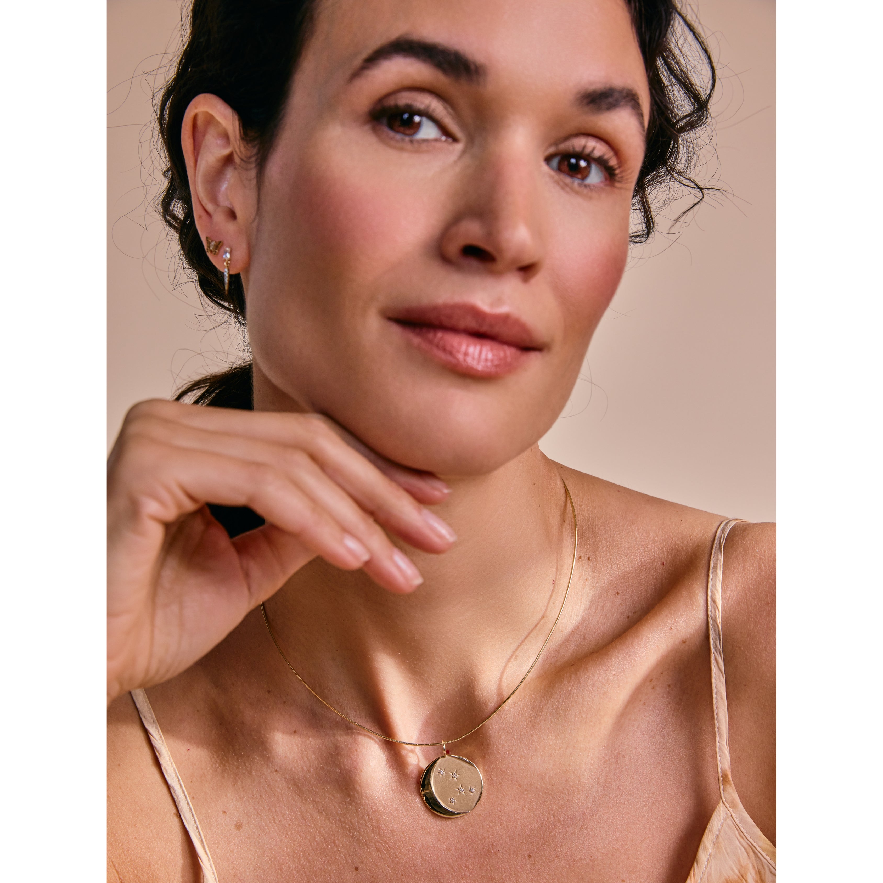 Model wearing the Estrella Charm on a gold chain, shown in a soft portrait setting