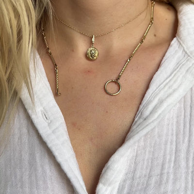 Close-up of layered gold necklaces featuring the Estrella Charm and coordinating pendants